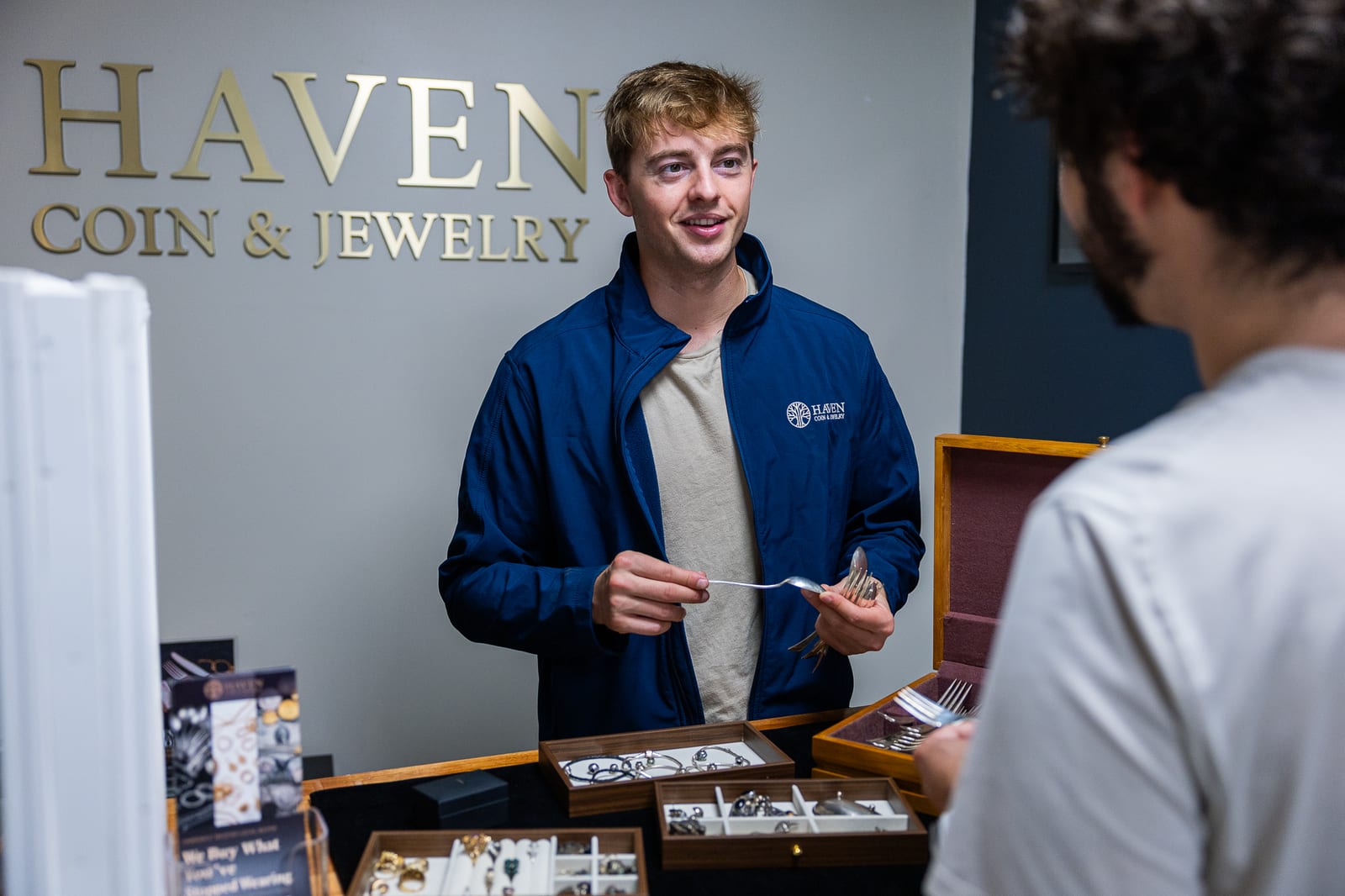 Haven Coin & Jewelry team member evaluating sterling silverware with customer