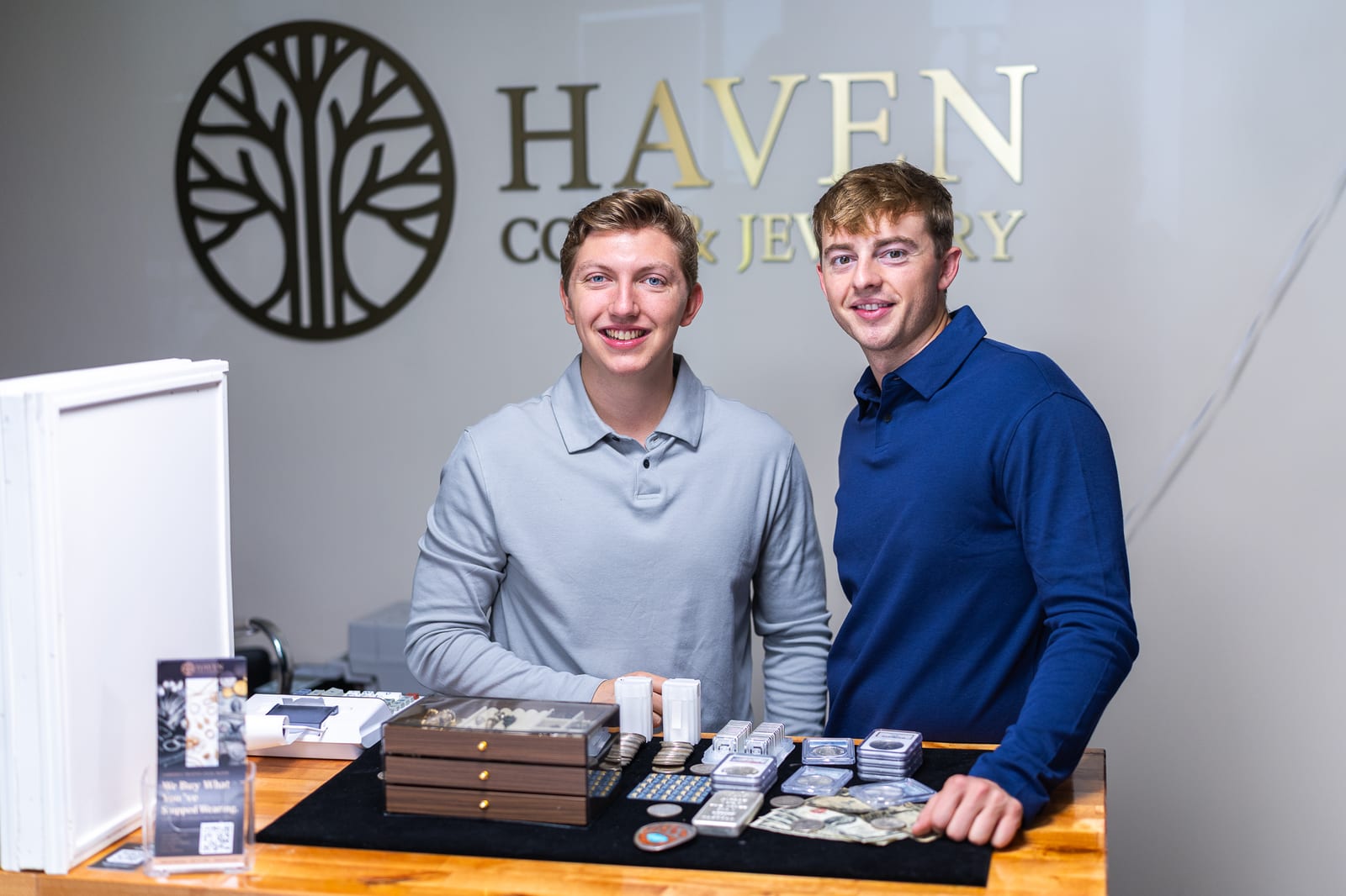 Haven Coin & Jewelry team smiling at the counter with coins and jewelry
